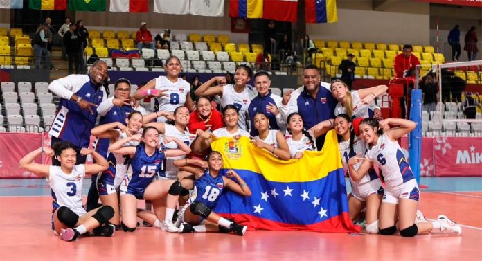 El equipo femenino de voleibol de Venezuela posa con su bandera, sonriendo y mostrando orgullo por su país.